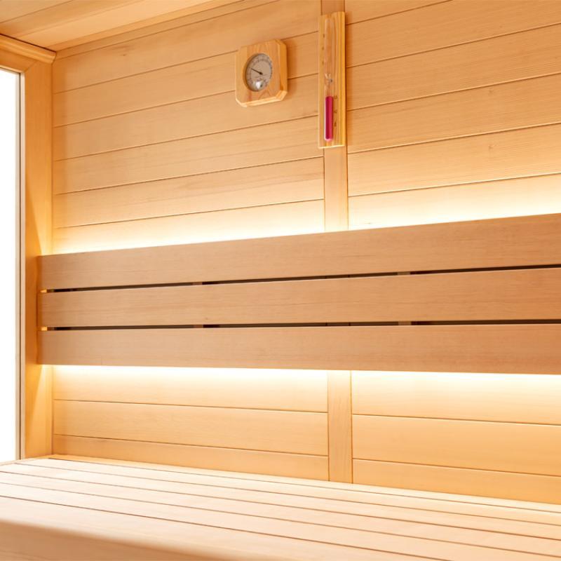 EAGO AWT E1620C Hemlock Sauna Innenraum mit Holzbänken, LED-Beleuchtung und analogem Thermometer an der Wand
