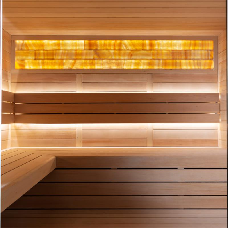 Innensicht einer hochwertigen Hemlock-Sauna mit Infrarotstrahler, Holzbänken und warmweißer Beleuchtung