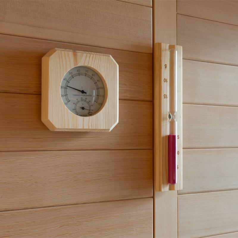 Holz-Thermometer und Hygrometer mit runder Anzeige an Saunawand montiert, daneben vertikales Holz-Saunathermometer mit rotem Anzeigeindikator