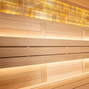 Moderne Saunakabine mit horizontalen Holzleisten in hellen und dunklen Tönen, warmweiße LED-Beleuchtung an Wänden und oberer Verglasung, luxuriöse Saunaeinrichtung mit Glasfront
