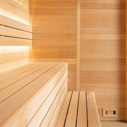 Innensicht einer Holzsauna mit hellen Hemlock-Holzbänken und vertäfelten Wänden, wärmend beleuchtet durch eingebaute LED-Leisten