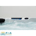 Seitliche Detailansicht des FinA Xaluna Outdoor Whirlpools mit beleuchtetem Wasserfall-Auslass, sprudelndem Wasser und integrierter Steuerung.