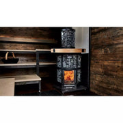 Harvia Legend 240 Saunaofen mit schwarzem Stahlrahmen und Sichtfenster, brennendes Feuer sichtbar, in rustikaler Blockhütte mit Holzwänden und Holzbänken installiert