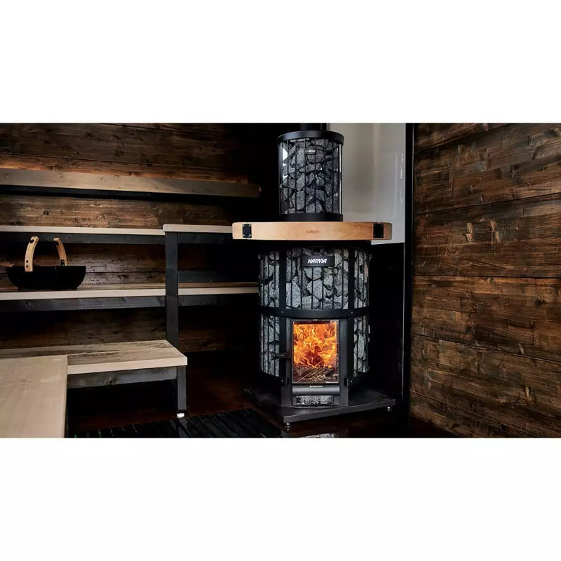 Harvia Legend 240 Saunaofen mit schwarzem Stahlrahmen und Sichtfenster, brennendes Feuer sichtbar, in rustikaler Blockhütte mit Holzwänden und Holzbänken installiert