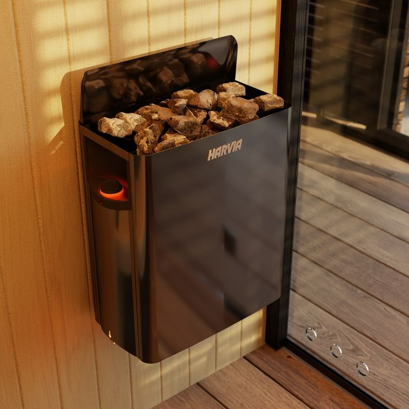 Harvia Saunaofen mit glühender Heizwendel und Saunasteinkorb gefüllt mit braunen Saunasteinen, montiert an Holzwand einer Innensauna
