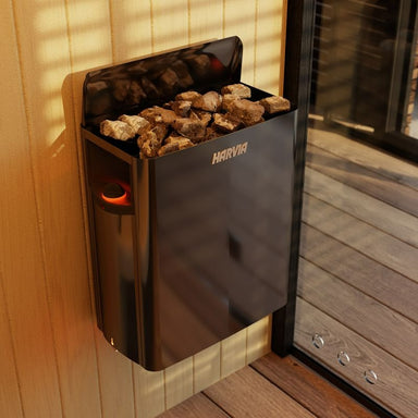 Harvia Saunaofen schwarz mit Steinen, montiert an Holzsauna