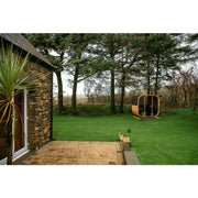 Hekla Cube 160/210/250 Gartensauna für 2/4/6 Personen im grünen Garten neben Steinhaus