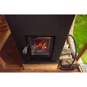 Hekla Cube 160/210/250 Gartensauna mit brennendem Feuer im Sichtfenster, schwarze Außenverkleidung auf Holzplattform