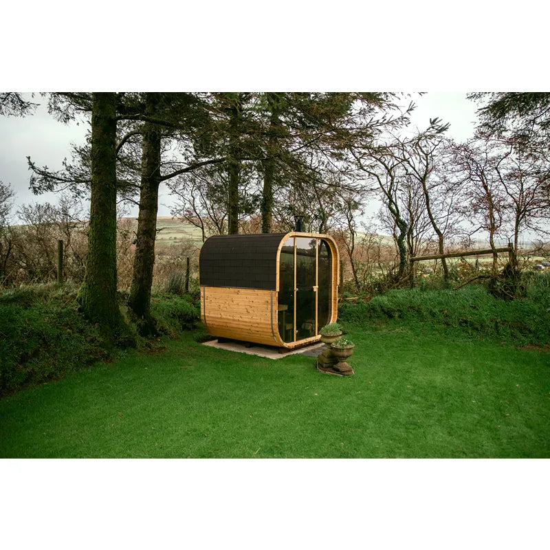 Hekla Cube 160/210/250 Gartensauna mit Holzfassade und schwarzem Dach in naturbelassener Umgebung