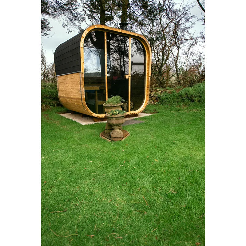 Hekla Cube 160/210/250 Gartensauna mit Holzverkleidung und großer Glasfront im grünen Garten