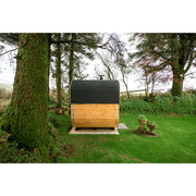 Hekla Cube 160/210/250 Gartensauna mit schwarzem Dach und Holzwänden im Garten zwischen Bäumen