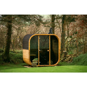 Hekla Cube 160/210/250 Gartensauna mit orangefarbenen Rahmen und Glastüren im Wald