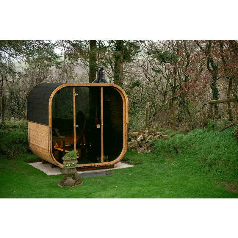 Hekla Cube Gartensauna mit Holzverkleidung und schwarzem Dach im grünen Garten