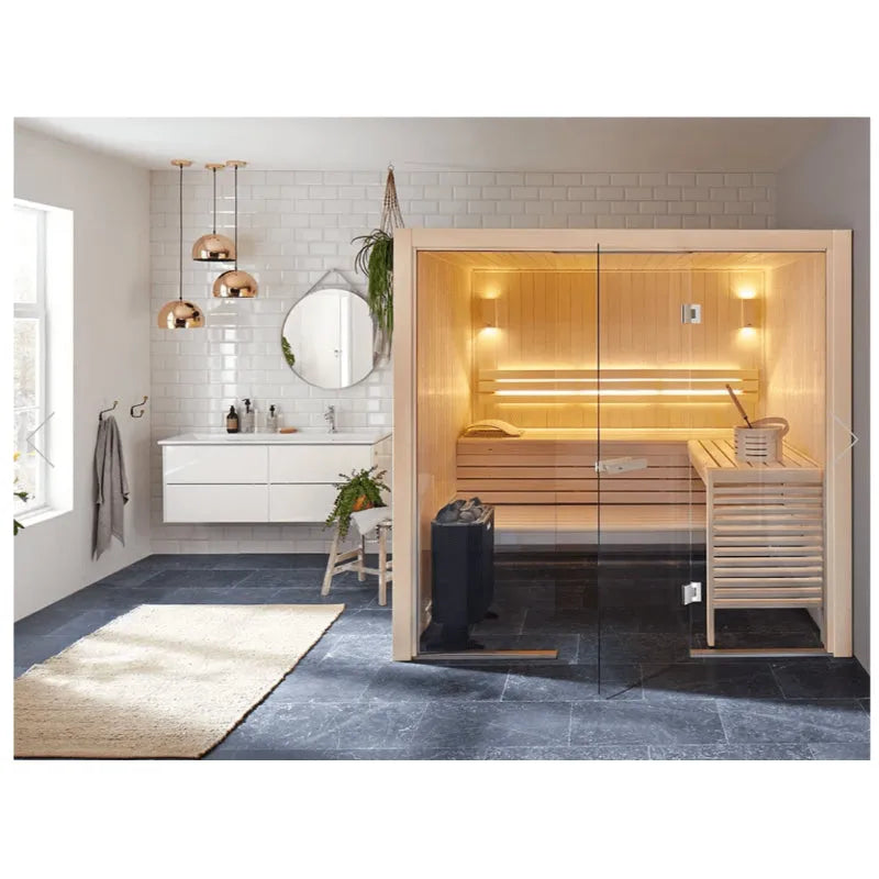 Modernes Badezimmer mit Holzsauna Helo Havanna mit LED-Beleuchtung, Glastüren und integriertem Saunaofen, daneben Waschtisch mit Spiegelwand und Kupferpendel­leuchten.