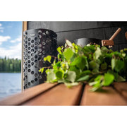 Helo Laine D Elektro-Saunaofen mit charakteristischem Hexagon-Design in moderner Sauna am See mit Blick auf Wald und Wasser