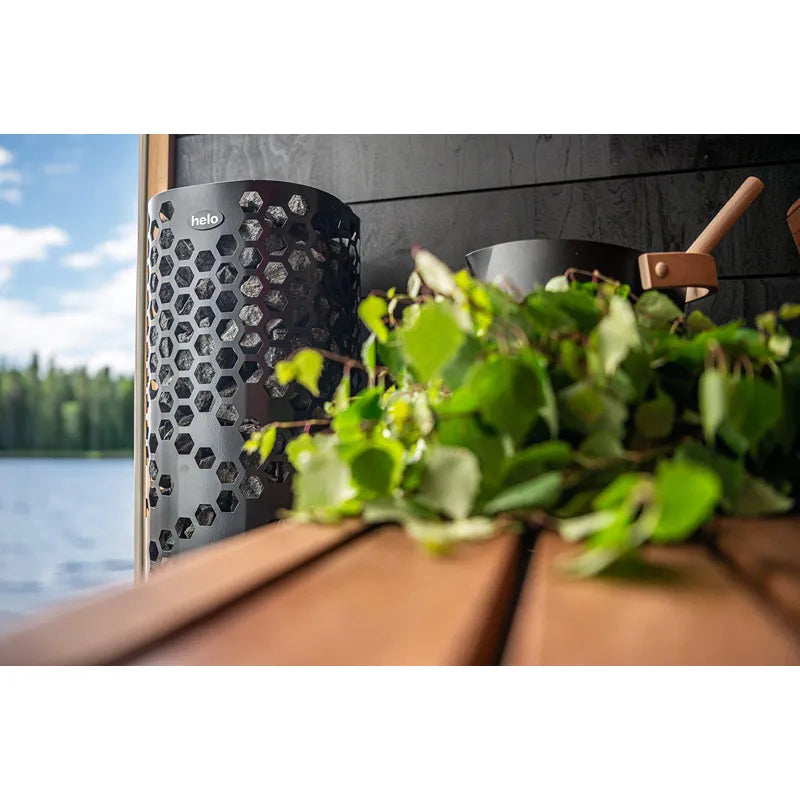 Helo Laine D Elektro-Saunaofen mit charakteristischem Hexagon-Design in moderner Sauna am See mit Blick auf Wald und Wasser