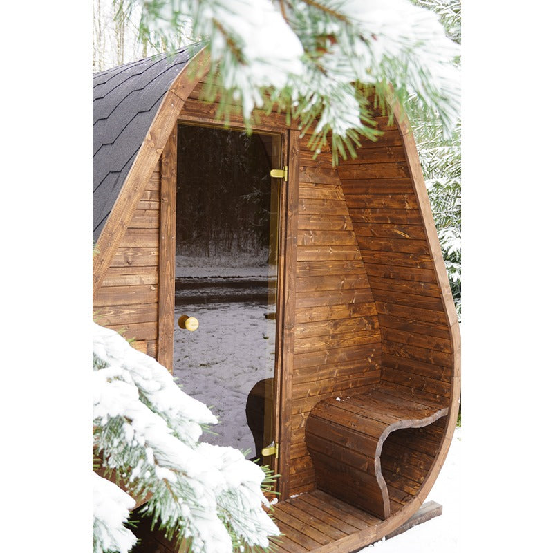 Detailansicht der Herkus Large Outdoor-Gartensauna in dunkelbrauner Holzoptik mit schwarzem Schindeldach und integriertem Vorraum, im verschneiten Wald aufgenommen.