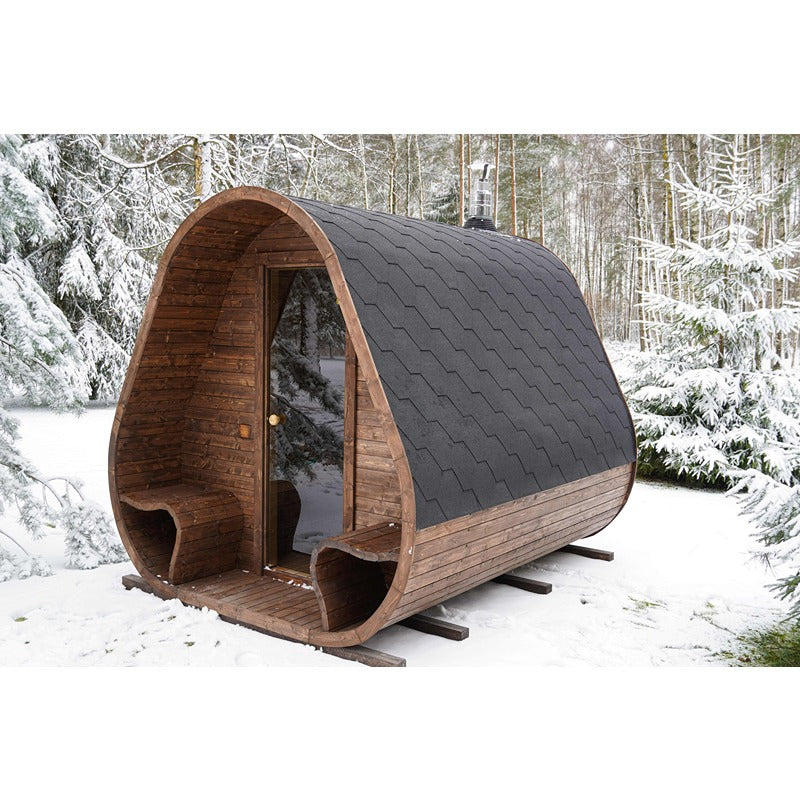 Herkus Large Outdoor-Gartensauna in dunkelbrauner Holzoptik mit schwarzem Schindeldach, integriertem Vorraum und Glastür, aufgestellt in verschneiter Waldlandschaft.