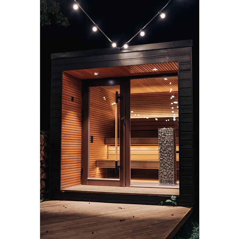 Huum Cliff elektronischer Saunaofen im modernen Gartensauna-Design bei Nacht beleuchtet, Standofen mit Holzverkleidung