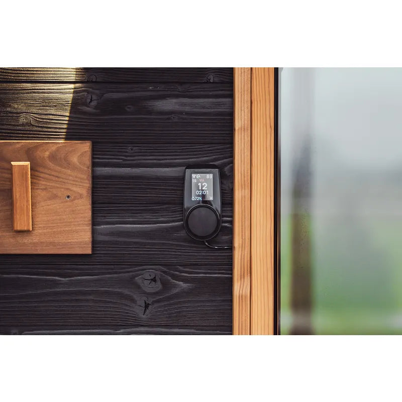 Huum Cliff elektronischer Saunaofen mit digitaler Steuerung an schwarzer Holzwand einer Gartensauna