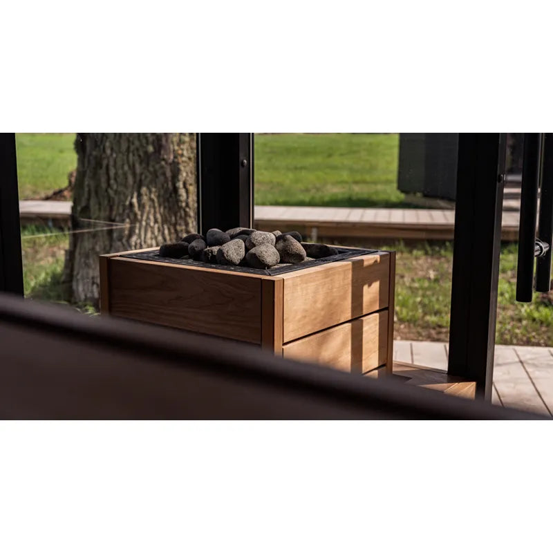 Huum Core Black elektrischer Saunaofen mit Steinen in moderner Holzummantelung auf Gartenterrasse