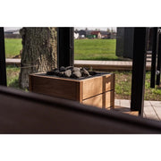 Huum Core Black Standofen in Gartensauna, schwarze und holzfarbene Konstruktion mit Saunasteinen, Gartenblick