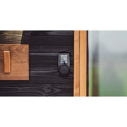 Huum Core Black elektrischer Saunaofen mit digitaler Steuerung an schwarzer Holzwand einer Sauna montiert