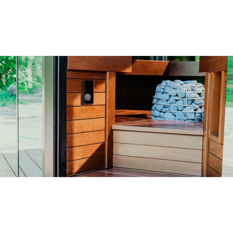 Huum Core Black Standofen Saunaofen in moderner Holzsauna mit offener Tür, schwarzer Heizelement und blauen Handtüchern