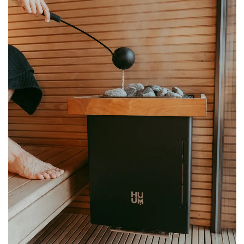 Huum Core Wall Combi Wandofen in moderner Sauna mit Saunasteine und Aufguss, schwarzer Saunaöfen