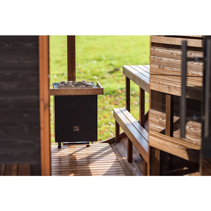 Huum Core Wall Combi Saunaofen 9 kW Wandofen mit Steinen in moderner Gartensauna auf Holzterrasse