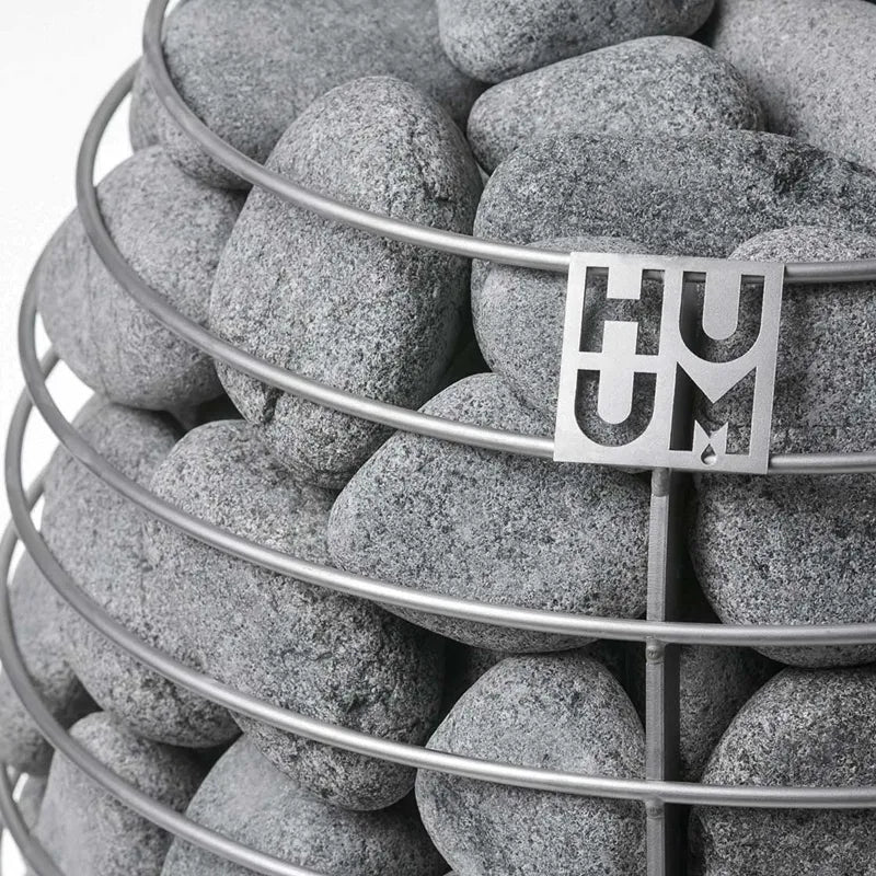 Huum Hive elektrischer Saunaofen Saunasteine mit Huum Branding auf Metallkorb