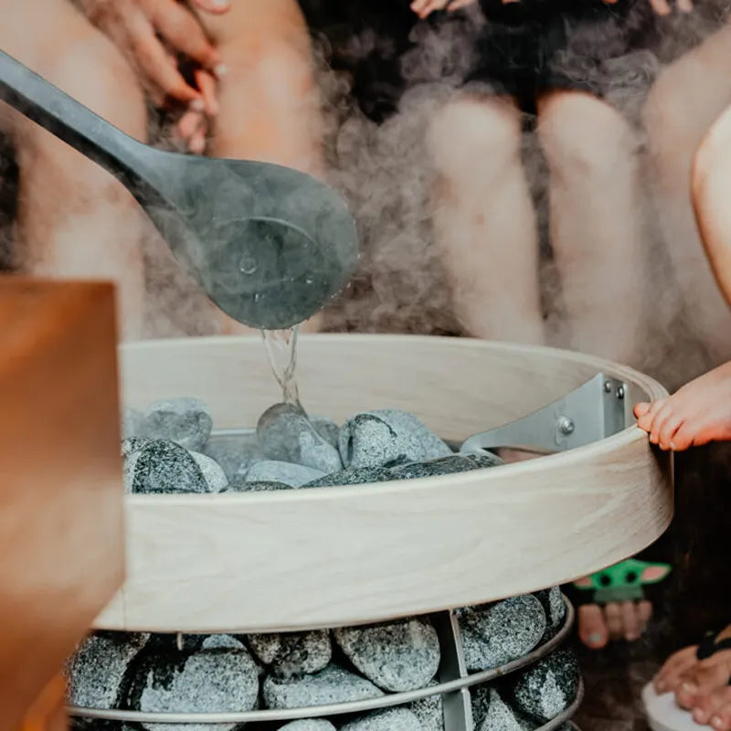 Huum Hive Mini Saunaofen mit Wasserschöpfer beim Aufguss, Standofen mit Saunasteinen