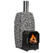 Holzbefeuerter HUUM Hive Flow LS Saunaofen mit sichtbarem Feuerraum und umliegenden grauen Saunasteinen im Metallkorb, modernes Design mit Edelstahlkaminrohr.