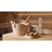 HUUM Kopfstütze aus Holz mit ergonomischem Design, präsentiert mit Saunazubehör in einer Saunaumgebung