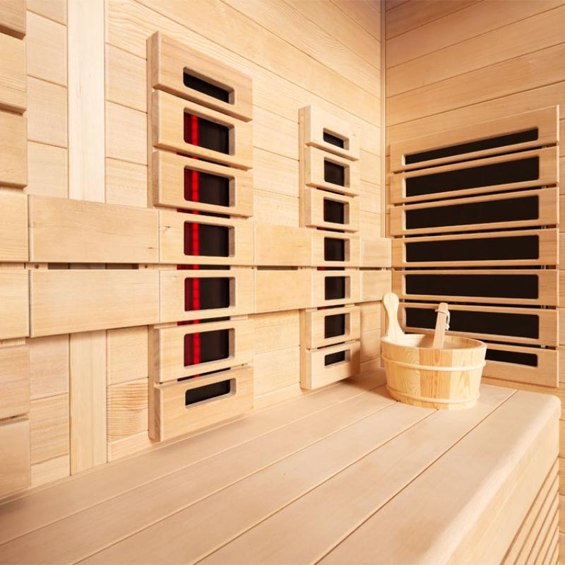 Innenansicht der EAGO AWT Infrarotkabine E1250A-IR mit hellen Hemlock-Holzwänden, mehreren Infrarot-Heizelementen mit roten Leuchtanzeigen und integrierter Holzbank für vier Personen