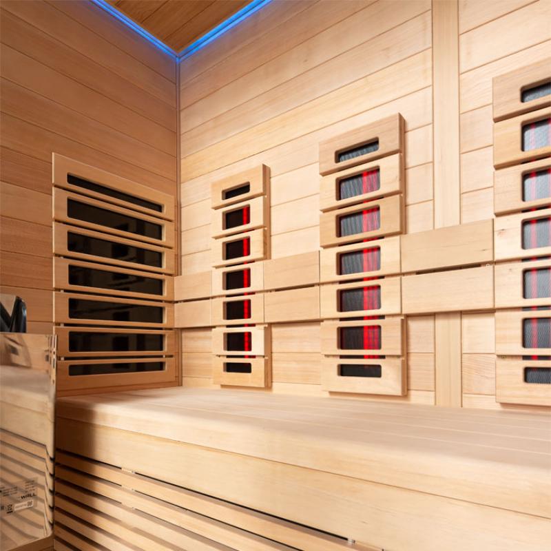 Innenansicht der EAGO AWT Infrarotkabine E1250A-IR mit Hemlock-Holzverkleidung, mehreren Infrarotheizpanelen und blauer LED-Deckenbeleuchtung für vier Personen.