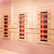 Drei nebeneinander angebrachte EAGO AWT Infrarotkabinen E1250B-IR aus Hemlock-Holz mit leuchtenden Infrarotstrahlern und Display, für Wellness im Innenbereich.