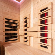 Modernes Infrarotkabinen-Interieur aus Hemlock-Holz mit mehreren Infrarot-Heizelementen in Rot- und Schwarztönen an den Wänden, Rosa-LED-Deckenbeleuchtung und Holzbänken
