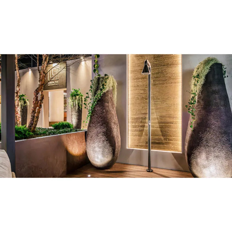 Moderne Gartendusche JEE-O cone 01 mit schlankem Chromständer in eleganter Showroom-Szenerie mit begrünten Keramikwand-Objekten und indirekter Beleuchtung