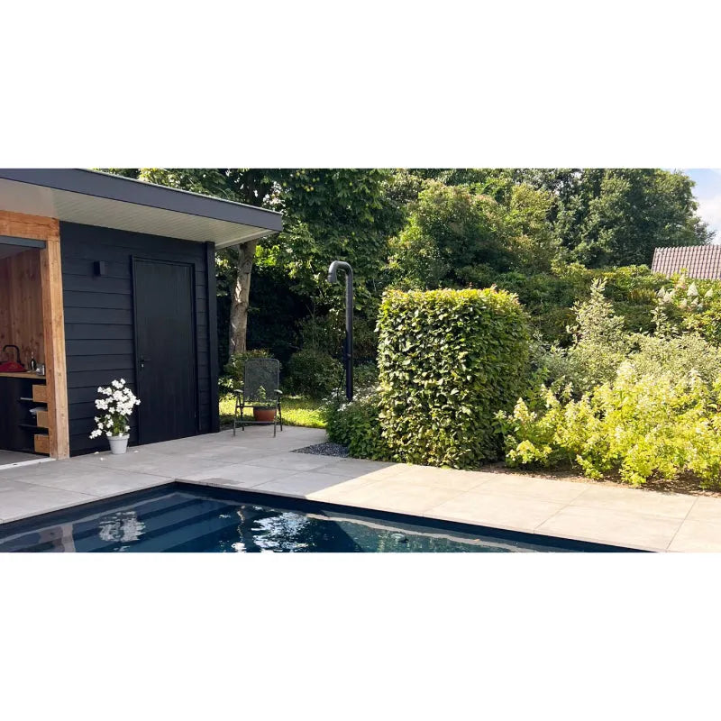 Moderne Gartendusche JEE-O soho 02 in schwarzer Ausführung neben Swimmingpool und zeitgenössischem Poolhaus mit grünen Hecken