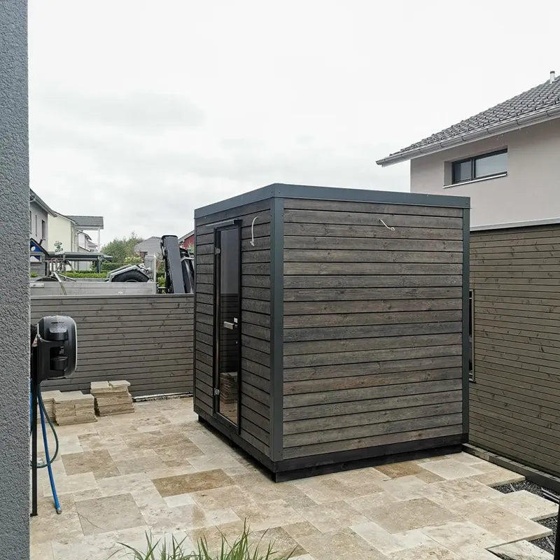 KOBA Block Gartensauna - Modernes Saunahaus mit schwarzem Holzdesign im Garten installiert