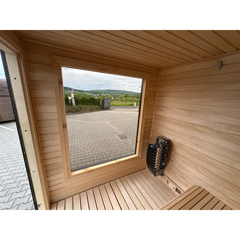 KOBA Cube Gartensauna Innenraum mit Holzbänken, großem Fenster und Saunaofen