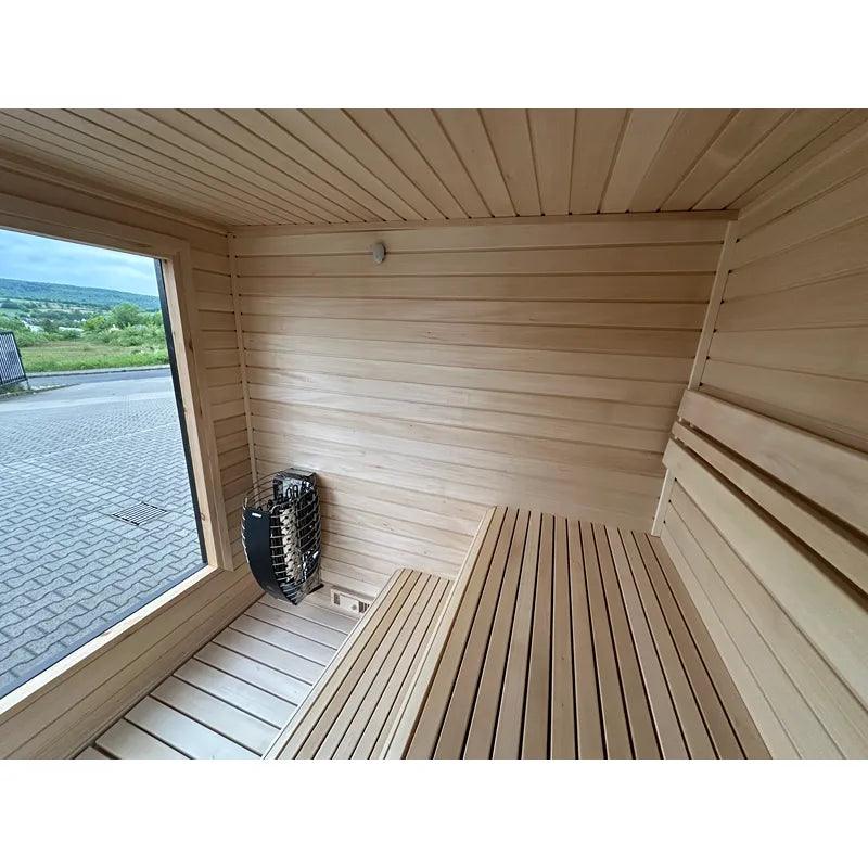 KOBA Cube Gartensauna Innenraum mit Holzbänken, Saunaofen und Glastür zum Garten