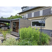 KOBA Cube Gartensauna mit moderner quadratischer Form im Garten neben Terrassenbereich und Bepflanzung