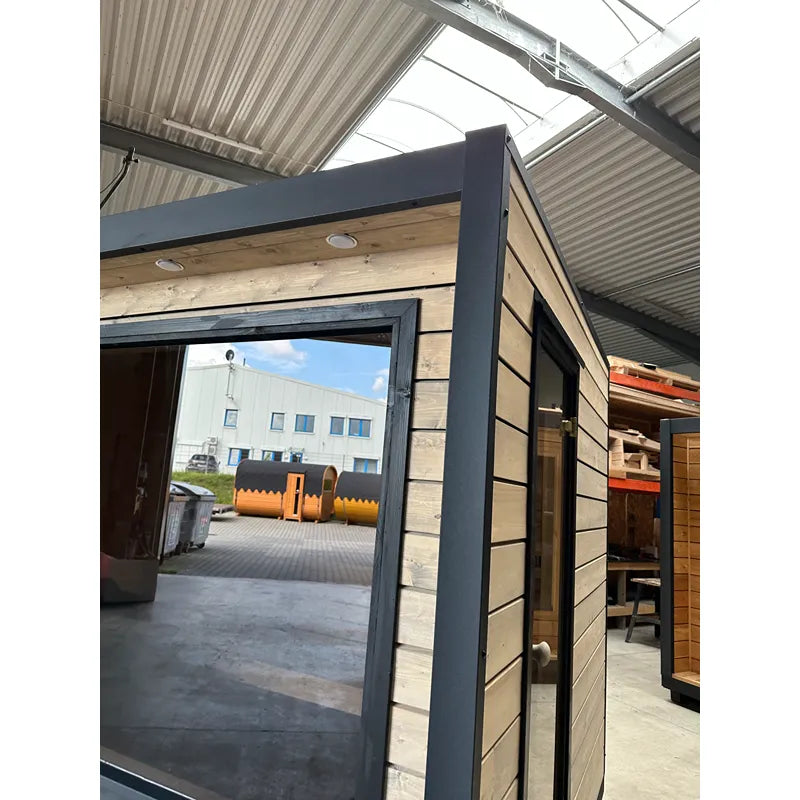 KOBA Cube Gartensauna - Moderne quadratische Form mit schwarzem Rahmen und Holzverkleidung in Lagerhalle