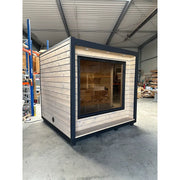 KOBA Cube Gartensauna moderne quadratische Form mit Holzverkleidung und großem Fenster in Lagerhalle