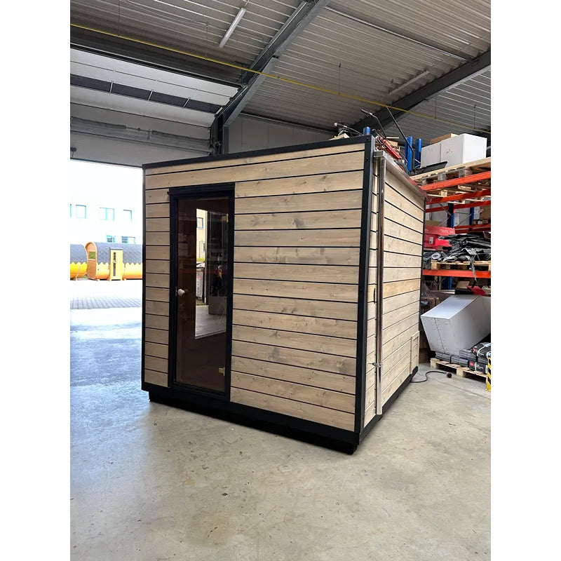 KOBA Cube Gartensauna - Moderne quadratische Form mit Holzverkleidung und schwarzem Rahmen in Lagerhalle
