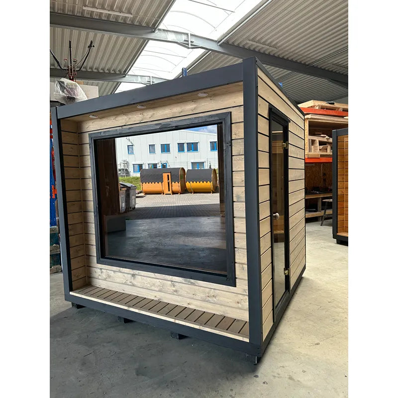 KOBA Cube Gartensauna - Moderne quadratische Form mit schwarzem Rahmen und Holzverkleidung in Produktionshalle