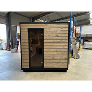 KOBA Cube Gartensauna moderne quadratische Form mit Holzverkleidung und schwarzem Rahmen in Lagerhalle