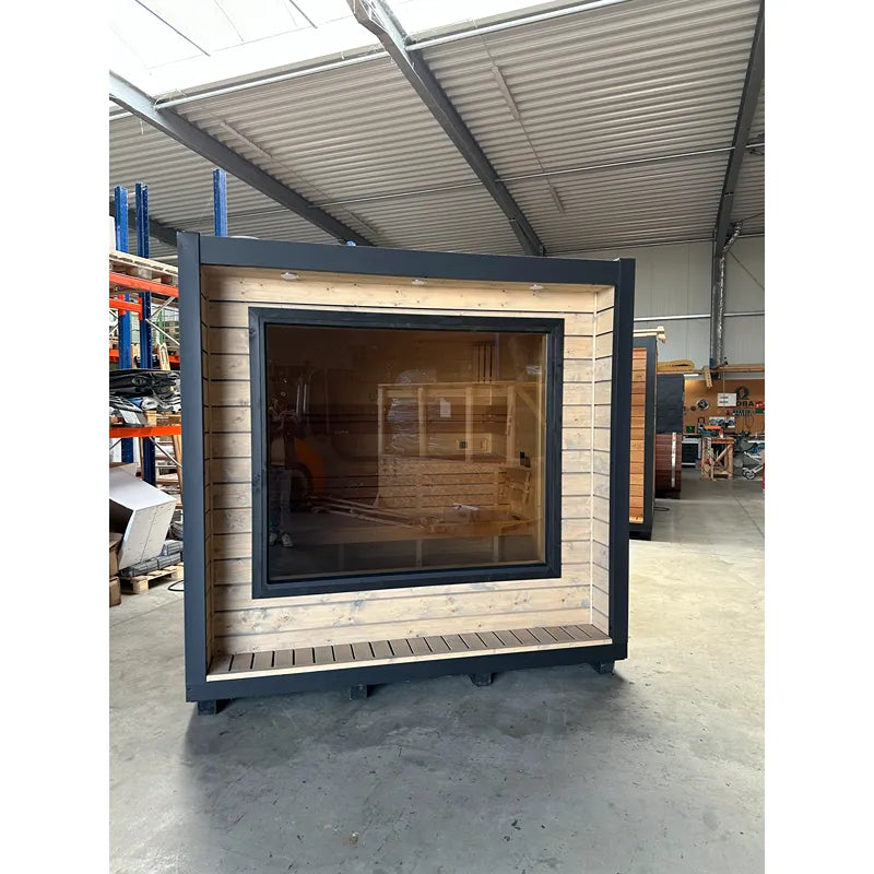 KOBA Cube Gartensauna moderne quadratische Form mit schwarzem Rahmen, Holzverkleidung und großem Fenster in Werkstatt